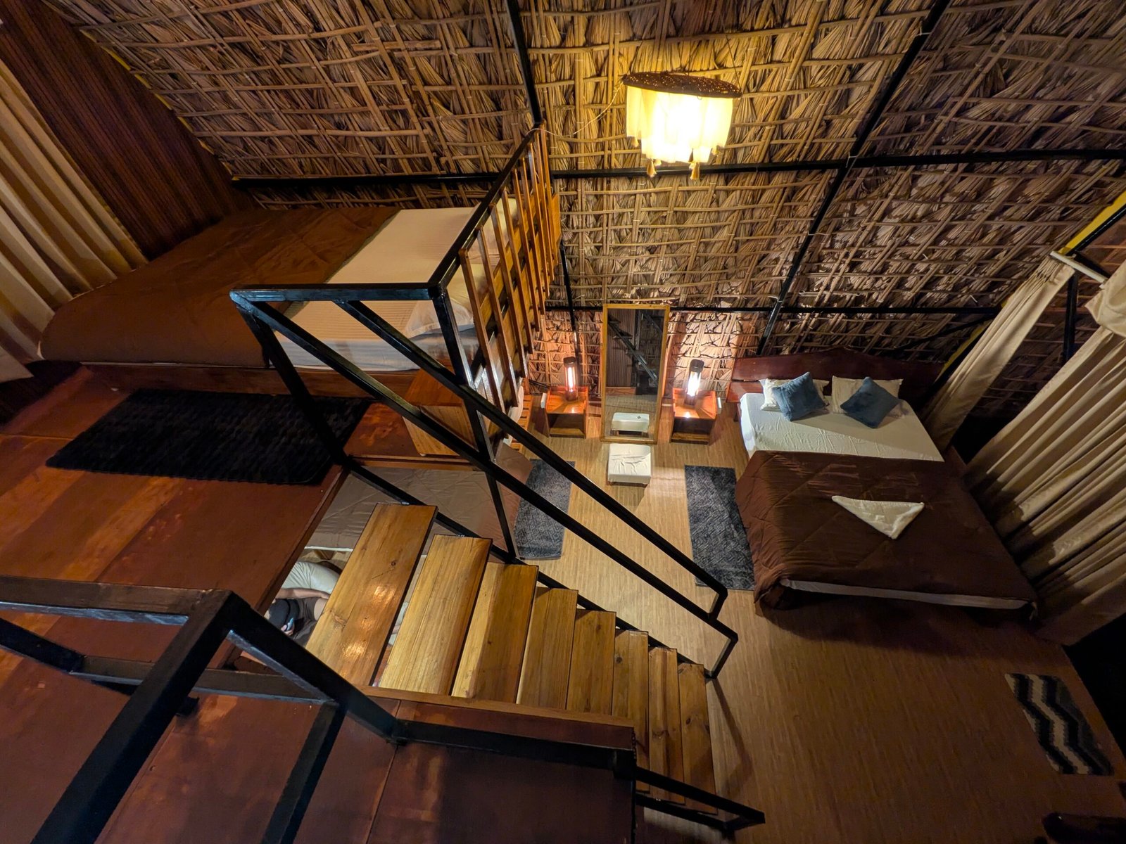 Full interior view of the cottage at night, showing the staircase, loft and two beds beneath the thatched vault
