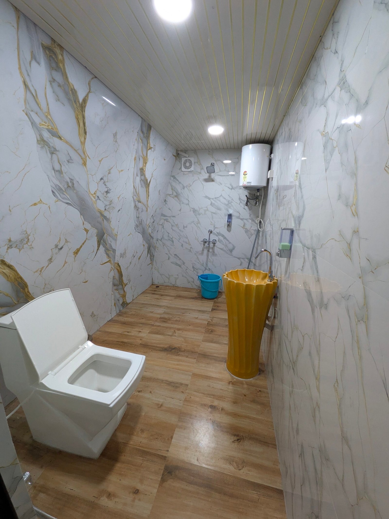 Marble-clad en-suite bathroom with geyser, pedestal basin, walk-in shower and Western toilet
